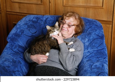 old woman in an armchair with a cat on hands