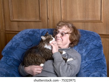 old woman in an armchair with a cat on hands