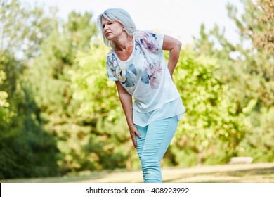 Old Woman With Back Pain While Walking In The Nature In Summer