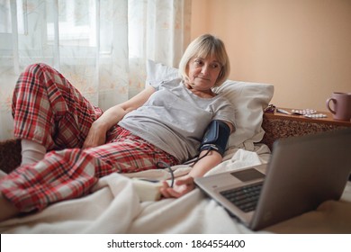 Old Woman In Bed Looking At Screen Of Laptop And Consulting With A Doctor Online At Home, Telehealth Services During Lockdown, Distant Video Call, Modern Tech Healthcare Application