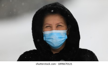 Old Woman In A Black Mink Coat Wearing A Medical Mask