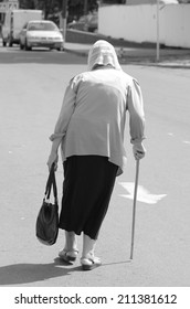 Old Woman With A Cane Back View.outdoors