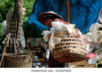 an old woman is carrying garbage to be reprocessed and sold for money at the landfill. - Shutterstock ID 2216295043