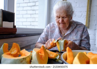 Old woman cuts and pills yellow pumpkin, cooking pumpkin soup, retirement life, selective focus
