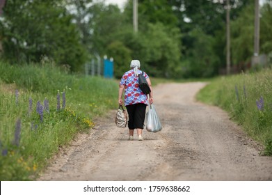 old woman drags heavy bags along the road