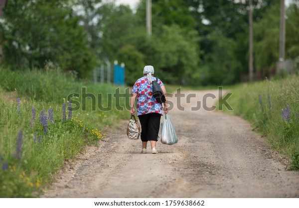old woman drags\
heavy bags along the road