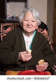 Old Woman Eating A Slice Of Bread At Home