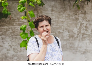 Old Woman Enjoying Eating Chocolate Outside - One Lone Senior Citizen Biting From A Cocoa Bar That Is Inside Her Mouth