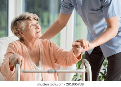 Old woman gets help with walking from a nurse