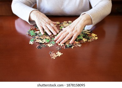 Old Woman Hands And Jigsaw Puzzle Pieces On A Table