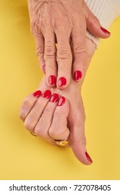 Old Woman Hands With Red Manicure. Female Manicured Hands On Yellow Background Close Up. Skin And Nails Spa And Care.