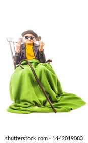 Old Woman With Hat And Sunglasses Sitting On The Chair Coverd With Green Blanket.