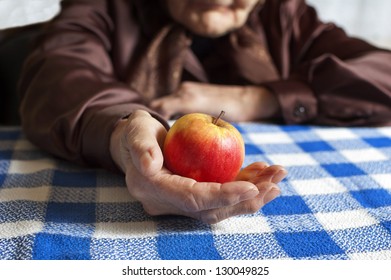 Old woman holding an apple. Selective focus on apple.