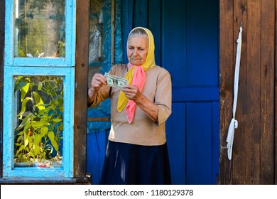 The Old Woman Is Holding Money In Her Hands. An Elderly Woman With Dollars In Her Hands