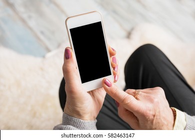 Old woman holding smartphone in her hands 