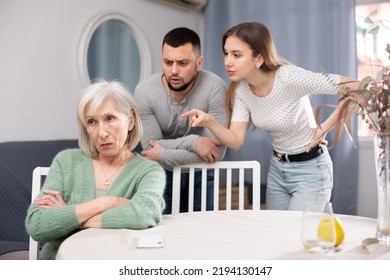 Old Woman Ignoring Her Daughter And Son-in-law Standing Behind And Arguing With Her At Home.