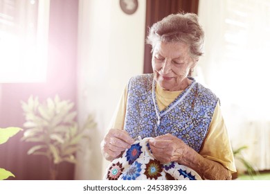 Old Woman Is Knitting A Blanket Inside In Her Living Room