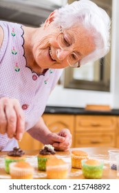 Old Woman Making And Decorating Cupcakes