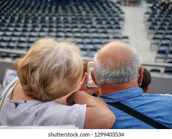 The Old Woman And Old Man, Pensioners Use A Video Call On Smartphone At The Concert Live