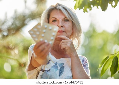 Old Woman With Medication In Hand In Nature