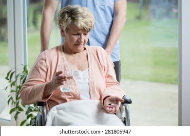 Old Woman On A Wheelchair Taking Pills