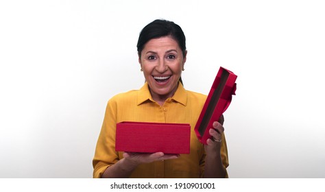 Old Woman Opens Gift Box, Isolated On White Background Studio Woman. The Old Woman Is Surprised By The Gift In The Box.