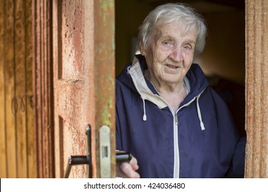 An Old Woman Peeks Out From Behind The Door Of His House.