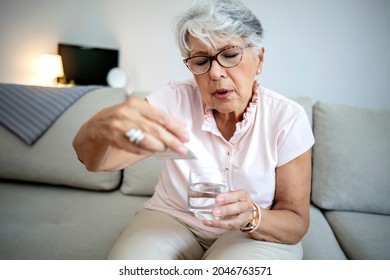 An Old Woman Peers, Frowning, At The Instructions On A Box Of Her Medication. Cropped Shot Of An Elderly Woman Holding A Box Of Medicine. Beautiful Senior Woman Looking Up Information About Medication