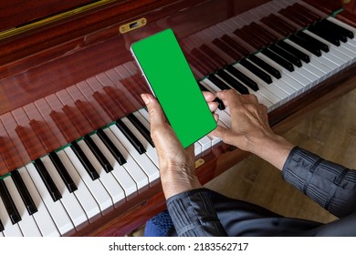 Old Woman Plays The Piano, Looks Into The Phone Notes. Chroma Key On Smartphone