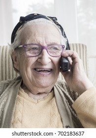 old woman, portrait of happy old senior woman talking on phone in living room at home. communication concept photo with happy senior or geriatric people talking on cell phone