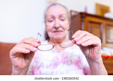 An Old Woman Puts On Her Glasses