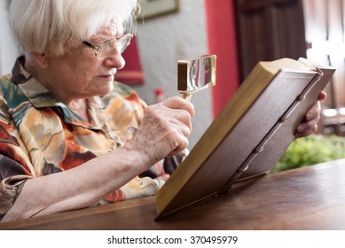 Old Woman Reading A Book With A Magnifying Glass