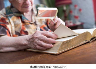 Old Woman Reading A Book With A Magnifying Glass