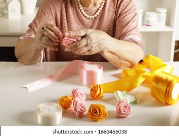 An Old Woman Of Retirement Age Weaves Roses From Colored Ribbons In Her Studio. Hand Made Art Crafts Theme
