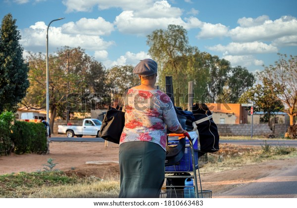 old woman with a shopping trolley walking in\
the streets of Gaborone  in\
Botswana
