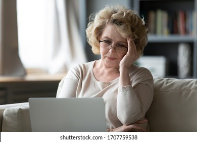 Old Woman Sit On Couch Using Laptop Looks At Screen Feels Stressed Not Understand Need Assistance With New App, Wrong Password, Exhausted, Older Generation And Difficulties With Modern Tech Concept