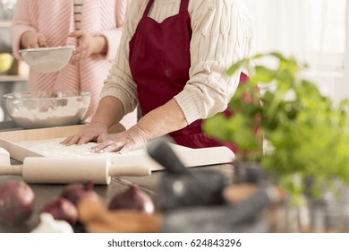 Old Woman Standing In A Kitchen And Baking A Cake