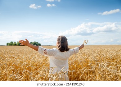 Old Woman  Stands With Her Back With Her Arms Spread Out To   Side In   Field With Golden Ears Of Cereal Crops 

