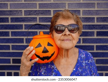 Old woman with sunglasses holding halloween pumpkin on day of the dead - Powered by Shutterstock