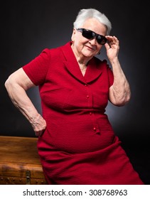 Old Woman In Sunglasses On A Dark Background