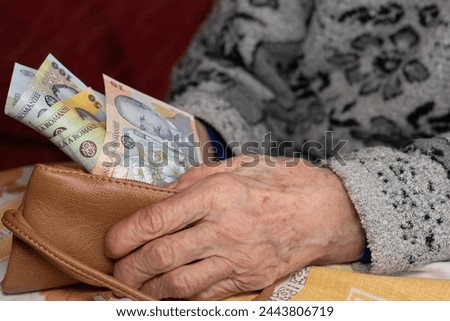 An old woman takes out a small amount of Romanian lei from her wallet, Financial concept, Rising cost of living and difficulties of retirees in Romania