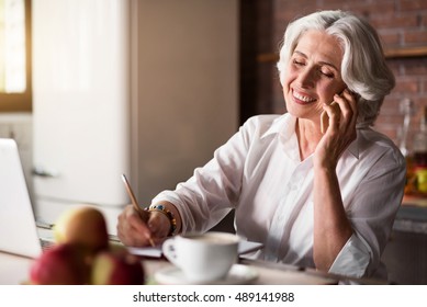 Old Woman Talking On The Phone While Taking Notes