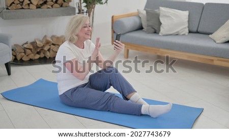 Old Woman Talking on Video Call on Smartphone while Sitting on Excercise Mat 