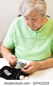 Old Woman With Test Strip And Blood Glucose Meter