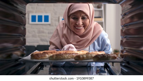 The Old Woman With A Turban Takes Out Delicious Pies From The Oven. Shooting From Inside The Oven.