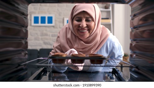 An Old Woman In A Turban Takes Out Delicious Cakes From The Oven. Shooting From Inside The Oven.