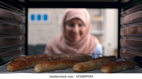 The Old Woman With A Turban Takes Out Delicious Pies From The Oven. Shooting From Inside The Oven.