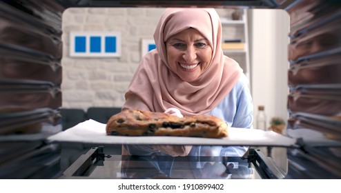 The Old Woman In A Turban Takes Out Delicious, Rich Grain And Olive Bread From The Oven. Shooting Through The Oven. 