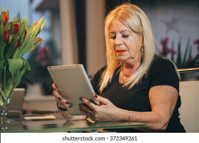 Old Woman Using Tablet Computer At Home