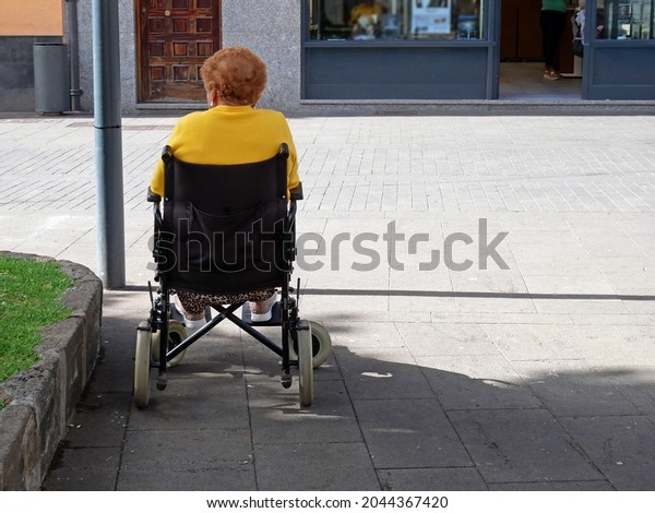 old woman using wheelchair on street in city,\
woman with disabilities can access anywhere in public place with\
wheelchair alone, outdoors
